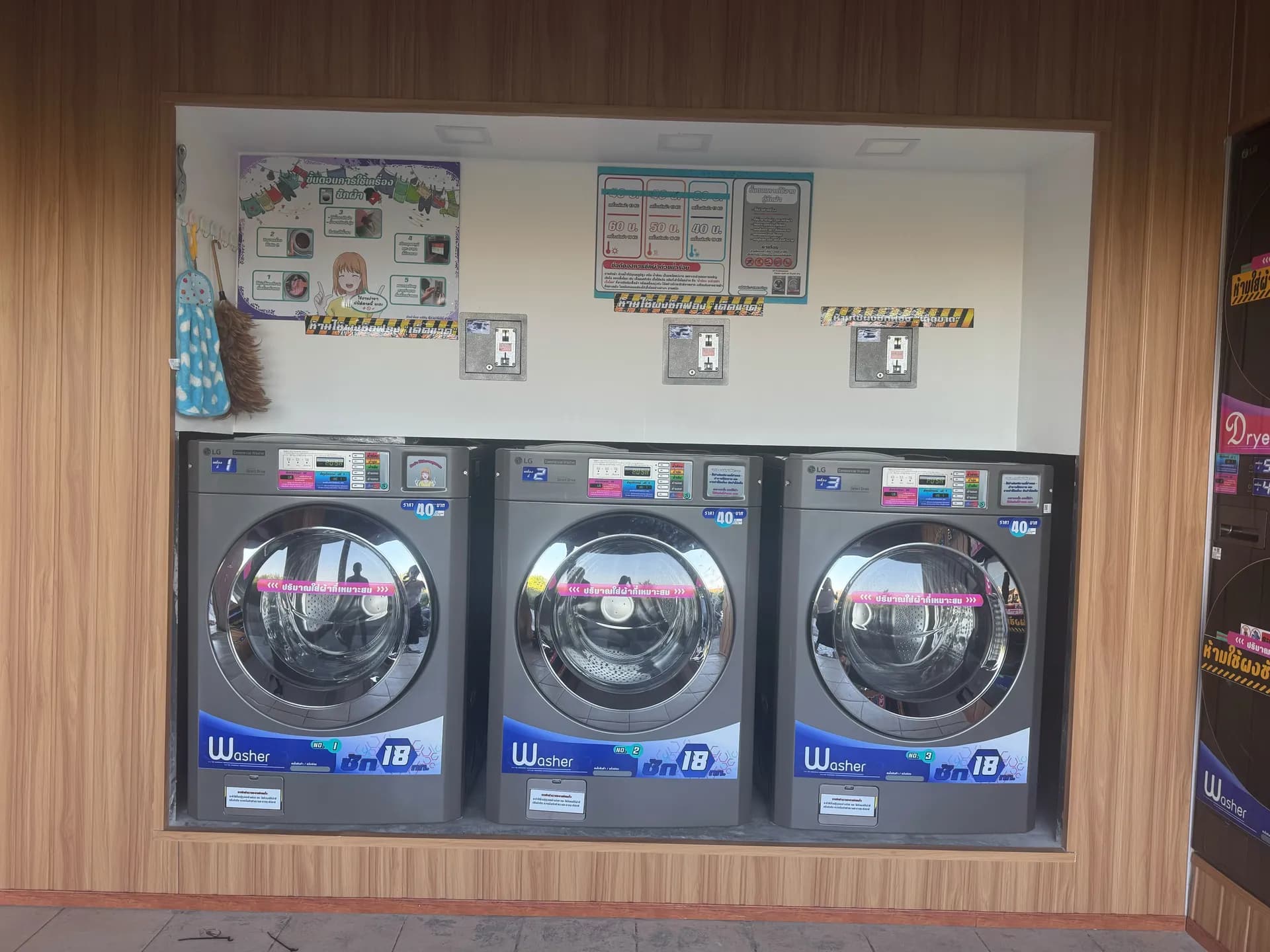 ภายในร้านสะดวกซัก เครื่องซักผ้าฝาหน้าสามเครื่องติดตั้งชิดผนังไม้
